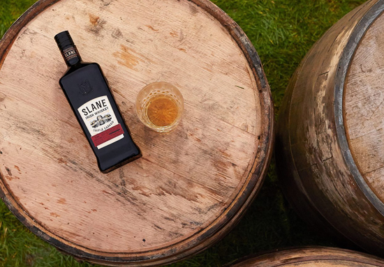 slane irish wiskey bottle on top of of cask barrel